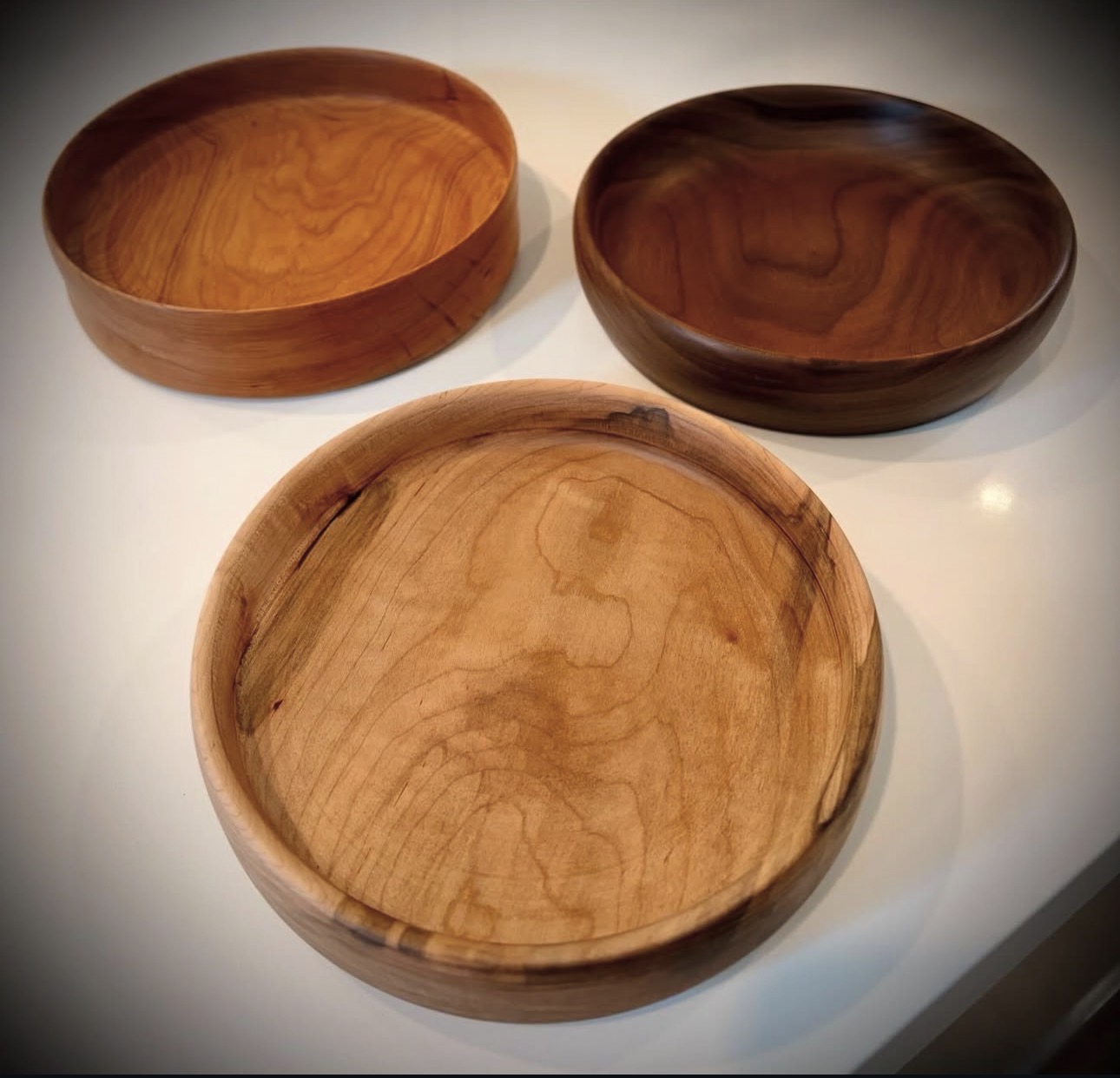 Three handcrafted wooden bowls in cherry, walnut, and spalted maple